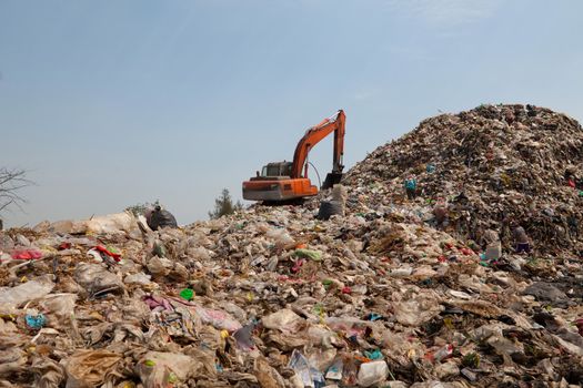 Backhoe moves trash in a landfill site, pollution, Global warming