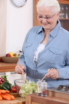 An old lady making a salad.