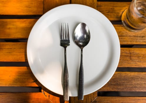 Fork and Spoon on white dish on wood table
