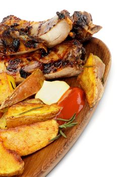 Arrangement of Barbecue Pork Ribs and Roasted Potato Wedges with Ketchup and Cheese Sauce closeup on Wooden Plate