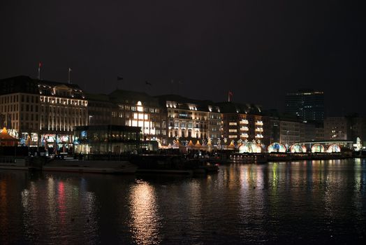 HAMBURG - DECEMBER 1, 2012: People visit traditional Christmas market around Alster river in Hamburg, Germany on December 1, 2012. The famous Hamburg Christmas market is located around the town hall and is a popular tourist attraction due to its gorgeous decorated stands.