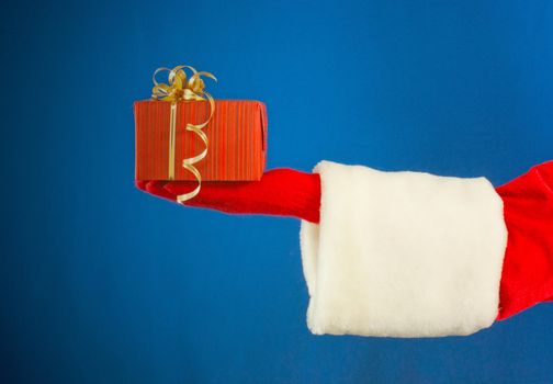 Santa's hand holding a present over blue background