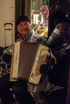 HAMBURG - DECEMBER 1, 2012: Old man playing the accordion in the cold winter evening at the Christmas market in Hamburg, Germany on December 1, 2012. The famous Hamburg Christmas market is located around the town hall and is a popular tourist attraction due to its gorgeous decorated stands.