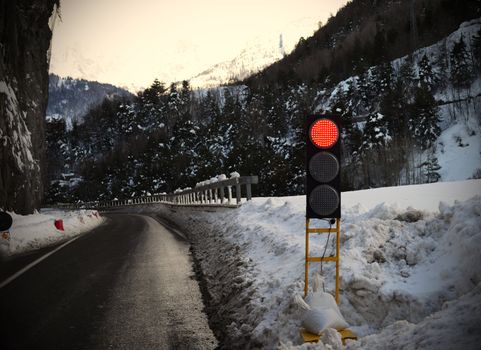 Mountains: red traffic light for avalanche, snowy weather, ice on street