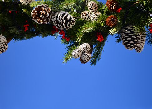 Festive christmas decoration with pine cones on blue sky with copy space
