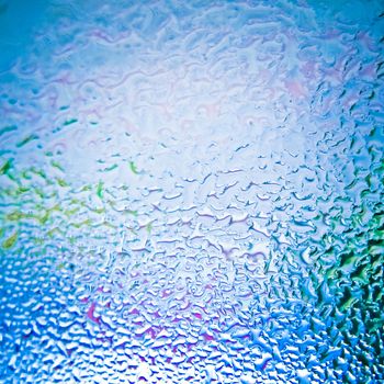 Drops of rain on glass on background of cloudy sky