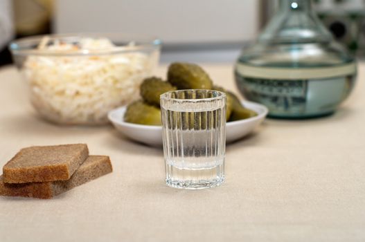 Wine-glass of vodka pickles and sauerkraut close up.