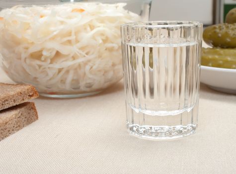 Wine-glass of vodka pickles and sauerkraut close up.