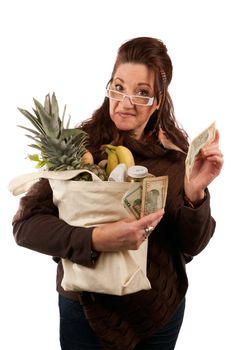 Middle aged female shopper smiling with a handful of cash acting proud of how much money she has saved on her grocery shopping bill.