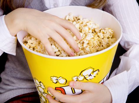 child's hand in a bucket of popcorn