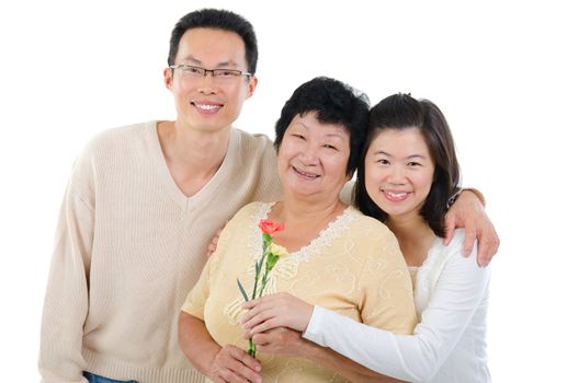 Asian family celebrates Mothers Day. Adult offspring giving carnation flowers to senior mother isolated on white.