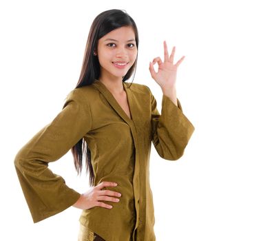 Southeast Asian Muslim female in traditional kebaya with long black hair gestures okay hand sign with great smile standing isolated on white background.