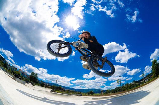 BMX rider jumps while doing cross bar trick.