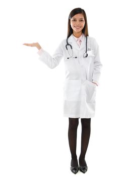 Full body Southeast Asian young female medical doctor holding her hand out and showing copy space for your product. Standing isolated on white background.