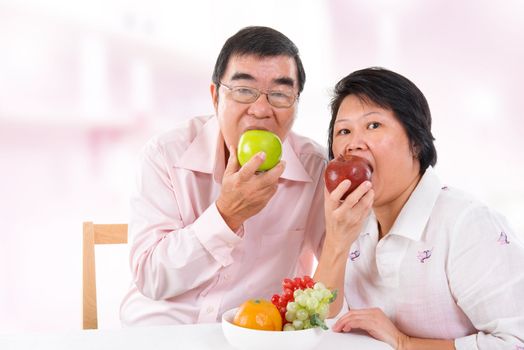 Southeast Asian mature couple eating fruits at home.