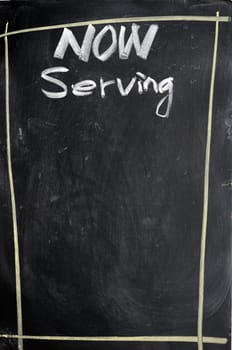 Menu of now serving written with chalk on a blackboard