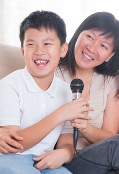 Southeast Asian family living lifestyle. Portrait of a happy Asian family singing karaoke through microphone in the living room