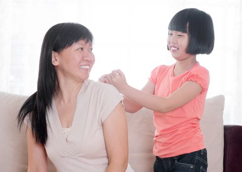 Filial piety concept. Southeast Asian child doing shoulder massage to her mother at home.