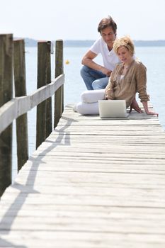 mature couple with laptop seated on pontoon