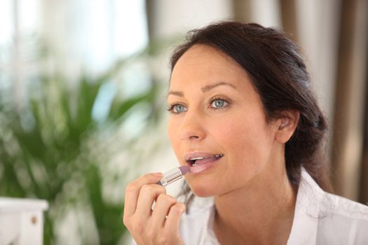 brunette putting on mauve lipstick