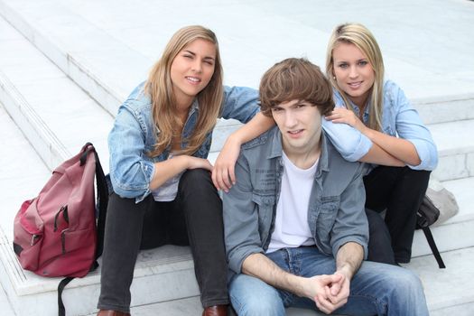 Three teenage friends sat on steps