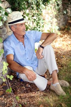 Mature man resting along a wall.