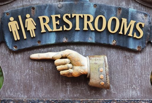 Sign with hand pointing direction to male and female restrooms