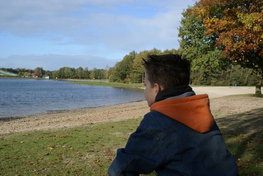 Young boy sitting by the water.