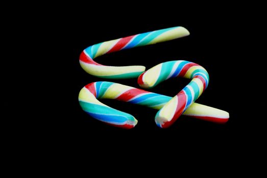 Three striped candy canes in front of black background.