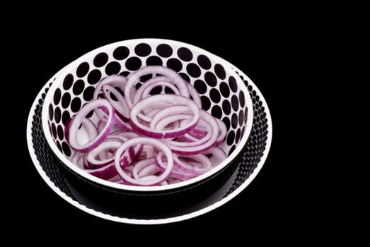 Isolated red onion rings in decorated bowl.