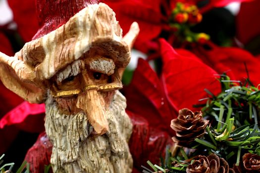 Wooden Statue of Santa Claus elf on poinsetta backdrop