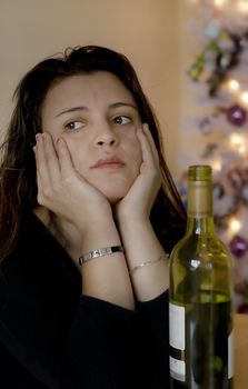 Depressed woman at christmas time and a bottle of wine. 