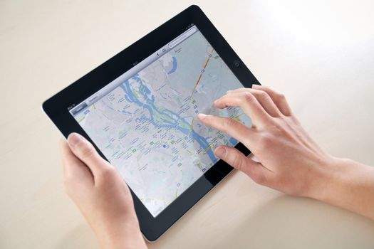 Kiev, Ukraine - December 03, 2011: Woman hands holding and touching on Apple iPad2 with Google Maps application on a screen. This second generation Apple iPad2 is designed and development by Apple inc. and launched in march 2011.