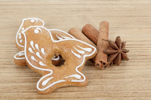 Gingerbread cookies birds hanging over wooden background with anise and cinamon