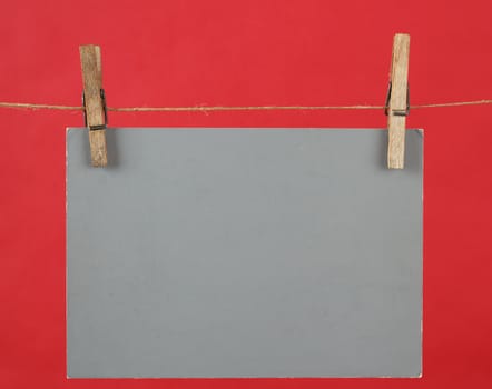 Memory note grey paper hanging on cord on red background