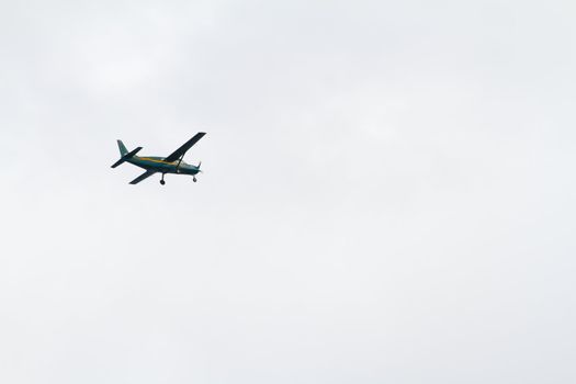 An airplane takes skydivers up into the clouds to perform this extreme sport. This plane is green with a propeller and a yellow strip.