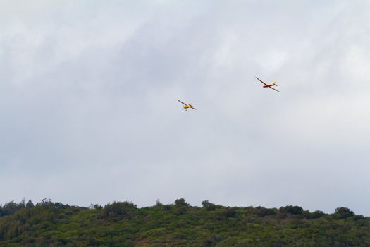 A glider is being towed by another airplane for a takeoff above the tropical mountains on the north shore of Oahu. This unique aircraft glides through the air with no engine.