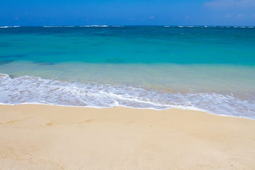 Beautiful tropical blue green water and a white sand beach on the north shore of Oahu in Hawaii. This image shows tropical paradise with a vacation getaway theme in a simple image.