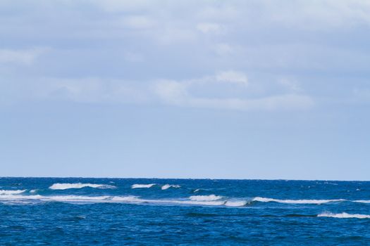 Blue water and a cloudy sky create this unique abstract landscape nature image of the Pacific Ocean. This is off the coast of the north shore of Oahu during a storm with rough water.