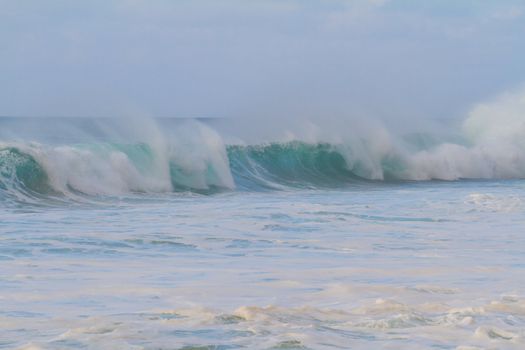 A giant wave breaking during a storm on the north shore of Oahu in Hawaii. These incredible waves have tons of white water and froth with hollow barrels and a dangerous rip current.