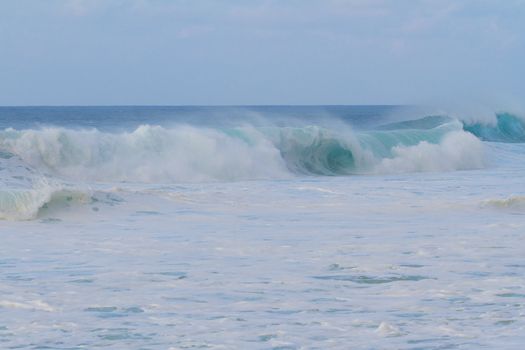 A giant wave breaking during a storm on the north shore of Oahu in Hawaii. These incredible waves have tons of white water and froth with hollow barrels and a dangerous rip current.