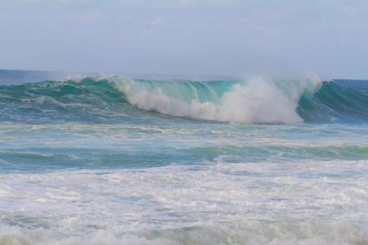 These huge waves with hollow barrels break off the north shore of Oahu in Hawaii during a big storm. These dangerous waves have major rip currents and a lot of power from the ocean but surfers are still lining up to surf.