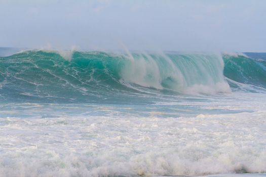 These huge waves with hollow barrels break off the north shore of Oahu in Hawaii during a big storm. These dangerous waves have major rip currents and a lot of power from the ocean but surfers are still lining up to surf.