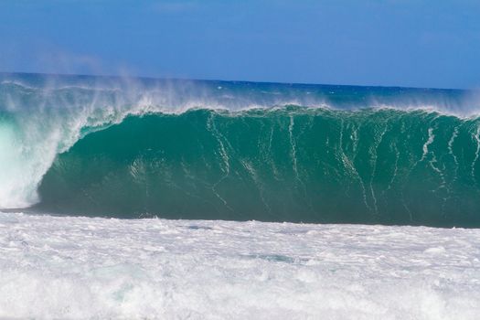 Large waves break off the north shore of oahu hawaii during a great time for surfers surfing. These waves have hollow barrells and are located at pipeline by sunset beach.