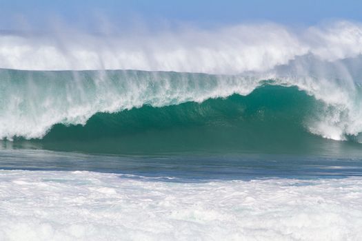 Large waves break off the north shore of oahu hawaii during a great time for surfers surfing. These waves have hollow barrells and are located at pipeline by sunset beach.