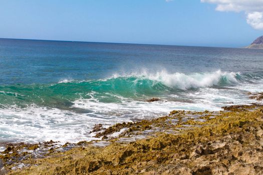 These perfectly clear waves form and break on some rocks in a dangerous spot on the west shore of Oahu in Hawaii. You can see right through the waves and the vibrant color of the ocean really shows.