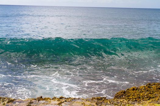 These perfectly clear waves form and break on some rocks in a dangerous spot on the west shore of Oahu in Hawaii. You can see right through the waves and the vibrant color of the ocean really shows.