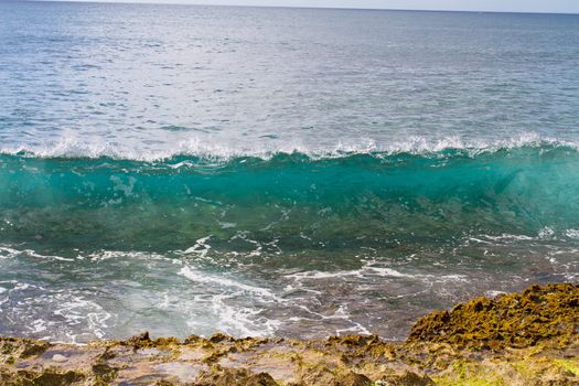 These perfectly clear waves form and break on some rocks in a dangerous spot on the west shore of Oahu in Hawaii. You can see right through the waves and the vibrant color of the ocean really shows.