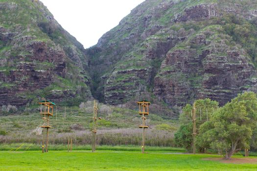 A camp on the north shore of Oahu in Hawaii has a high ropes stunt course for training and fun among the tropical vegetation and hills in the background.