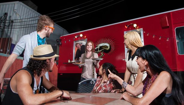 Cheerful waitress bringing orders to people at pizza truck